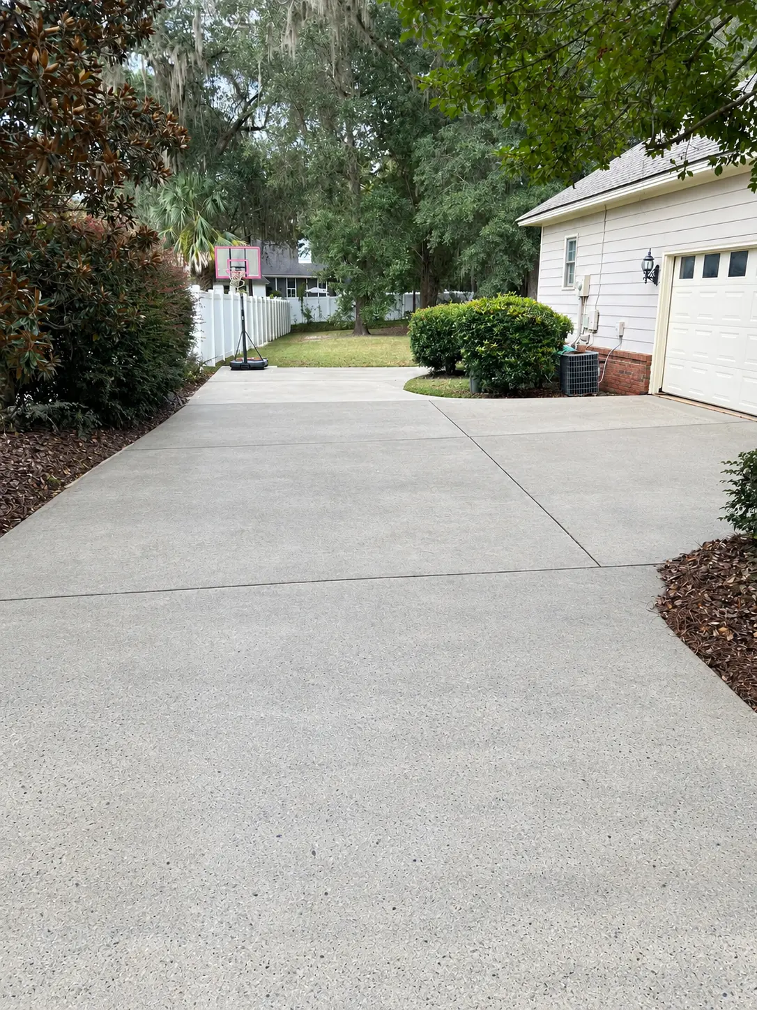 Clean concrete driveway and walkway beside a white home